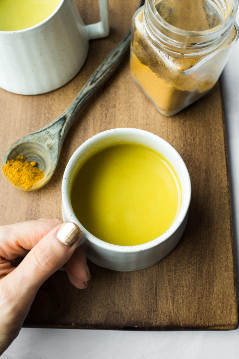 hand grasping mug of golden milk