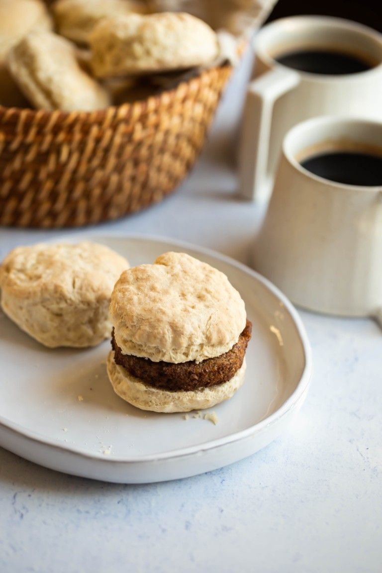 biscuits with vegan sausage on white plate and coffee