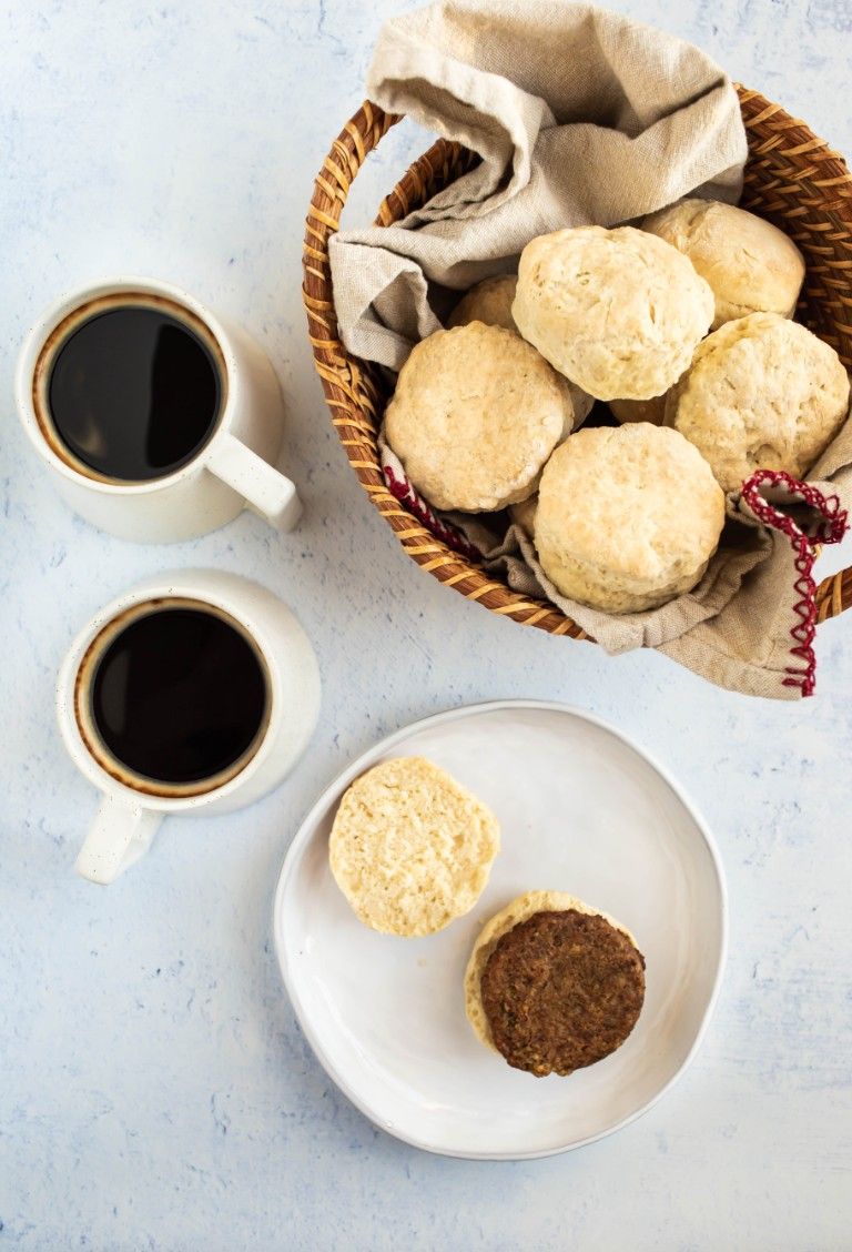 overhead shot of biscuit on white plate next to basket of biscuits