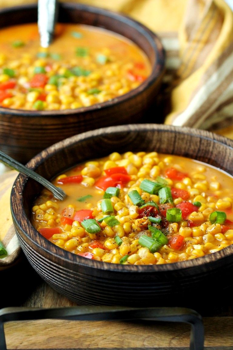 wood bowl with corn soup and spoon on tray