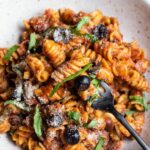 white bowl with italian pasta and fresh basil with black fork