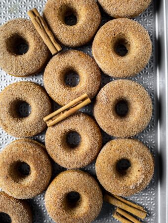 overhead view of several baked vegan apple cider donuts with cinnamon sticks