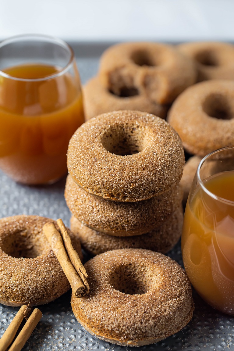 several donuts in between 2 glasses of apple cider