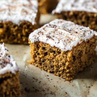 closeup of slice of pumpkin cake with frosting and fresh nutmeg and cinnamon