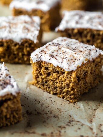 closeup of slice of pumpkin cake with frosting and fresh nutmeg and cinnamon