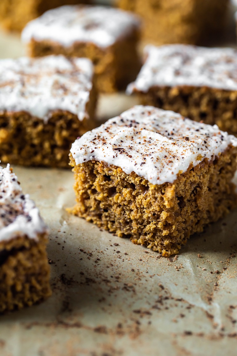closeup of slice of pumpkin cake with frosting and fresh nutmeg and cinnamon