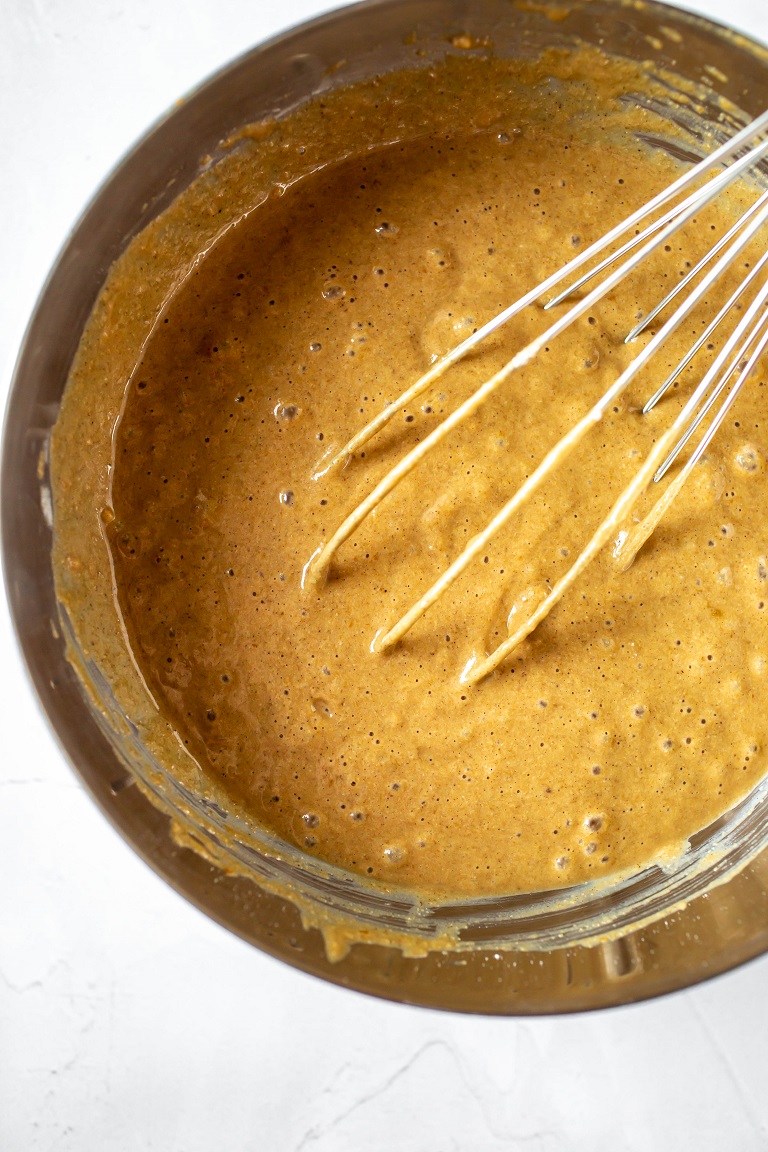 vegan pumpkin cake batter with large whisk in metal bowl