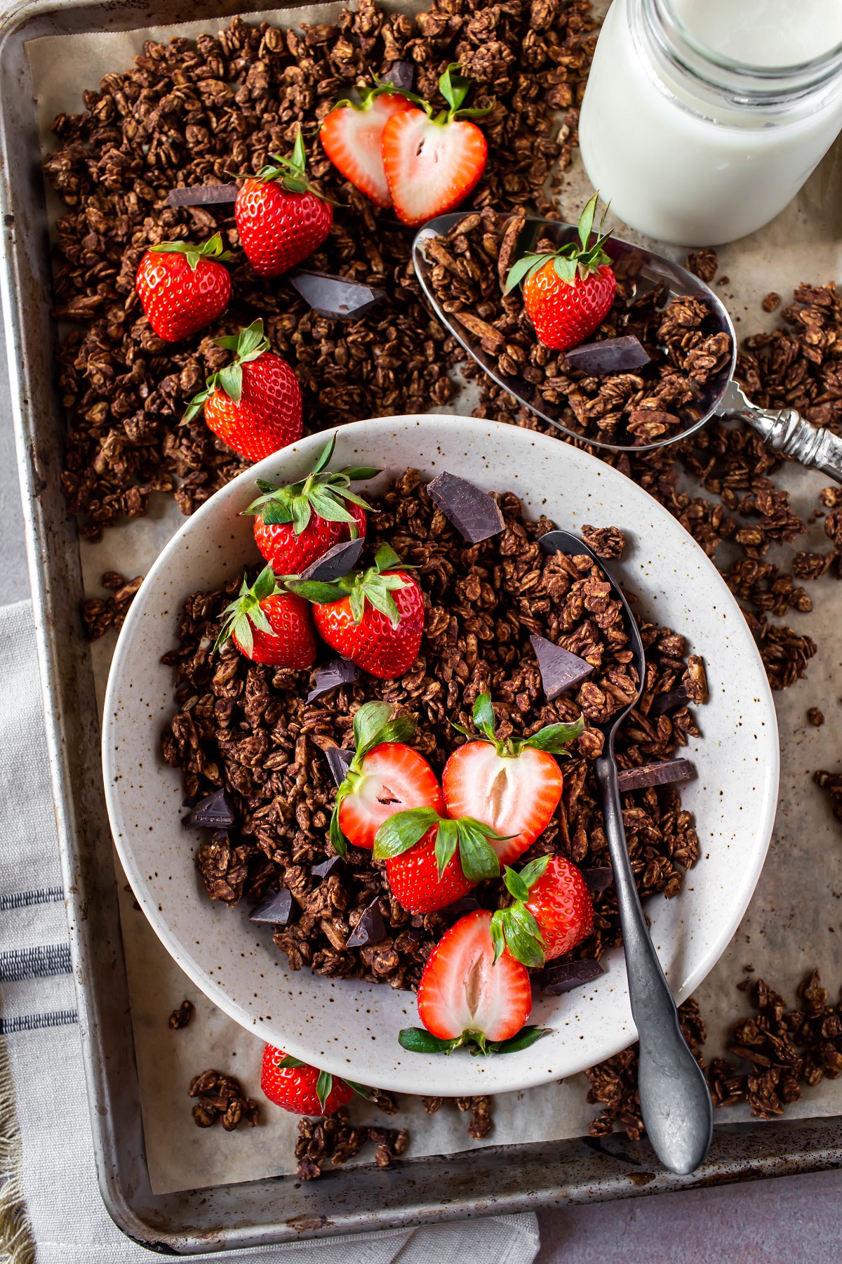 closeup of bowl of chocolate granola with spoon and strawberries