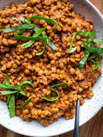 closeup of smoky instant pot lentils in bowl with spoon on wood platter