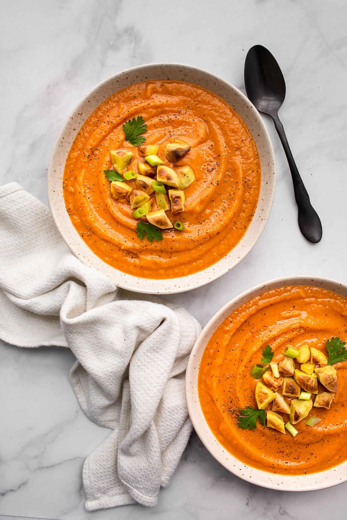 overhead shot of 2 white bowls of instant pot sweet potato soup with towel