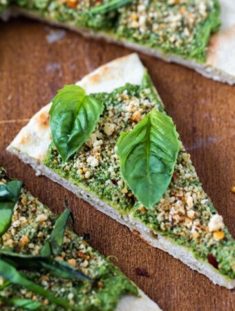closeup of vegan pesto flatbread pizza slice on wood board